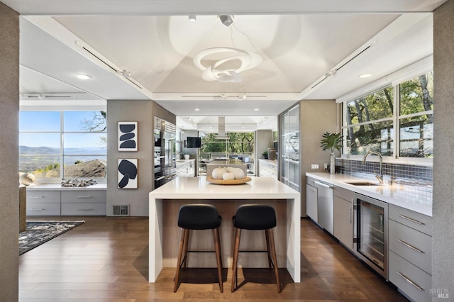 kitchen featuring wine cooler, a spacious island, sink, gray cabinets, and a healthy amount of sunlight