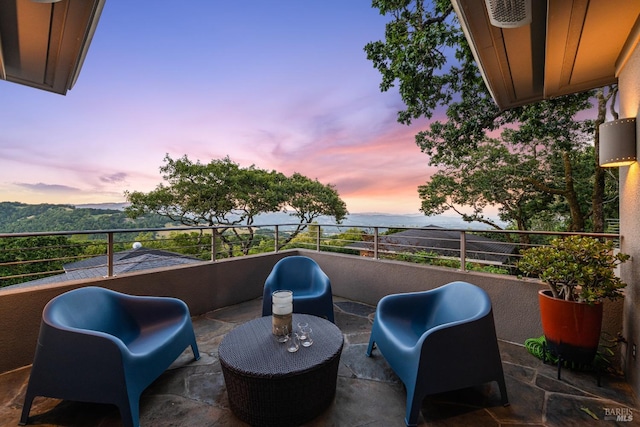 patio terrace at dusk featuring a balcony