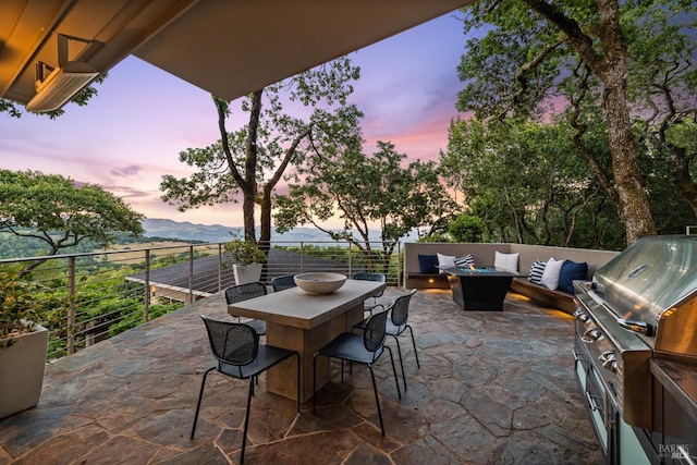 patio terrace at dusk with a grill and an outdoor living space with a fire pit