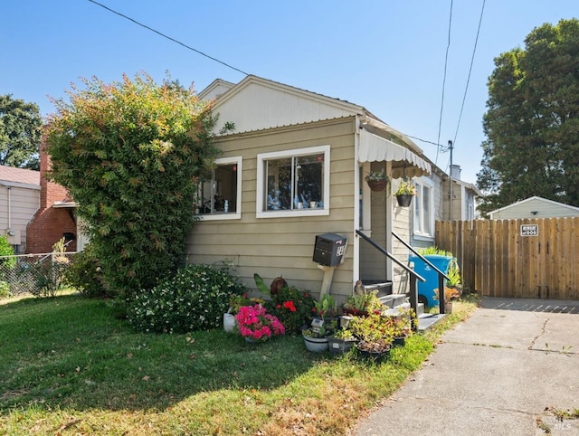 bungalow featuring a front lawn, fence, and entry steps