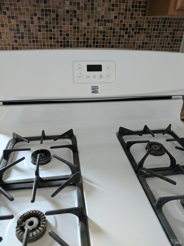 room details featuring decorative backsplash and white gas range oven