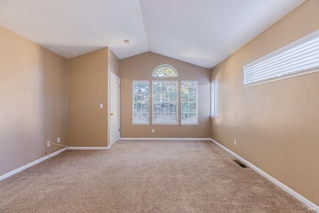 unfurnished room with lofted ceiling and light colored carpet