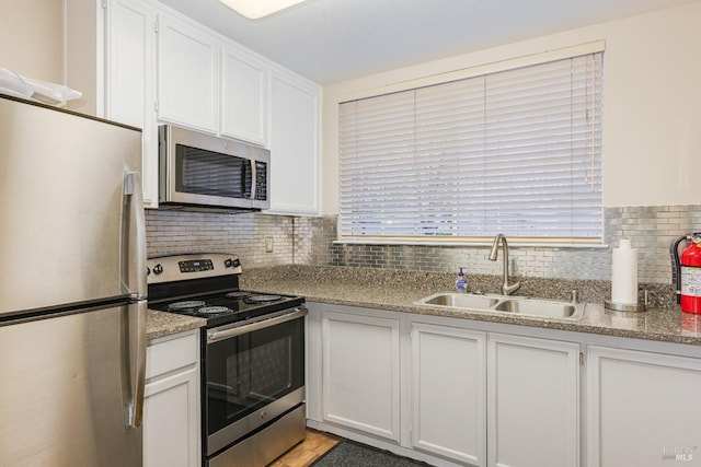 kitchen with white cabinets, appliances with stainless steel finishes, tasteful backsplash, and sink