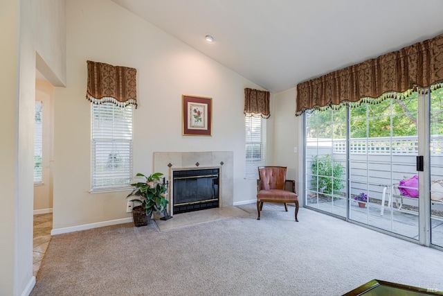 living area with a tiled fireplace, light carpet, and high vaulted ceiling