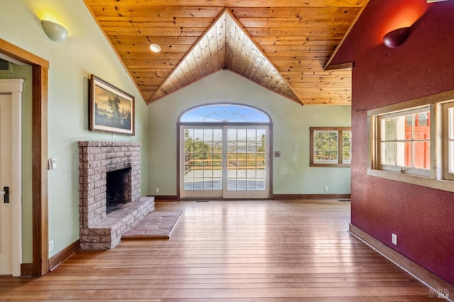 unfurnished living room with lofted ceiling, light wood-style flooring, a fireplace, and a wealth of natural light