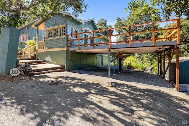 back of property featuring gravel driveway, stairs, and a deck