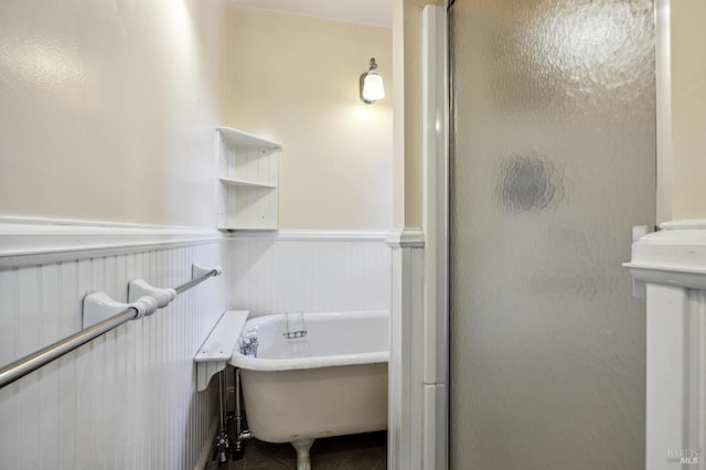 full bathroom featuring a wainscoted wall, a freestanding tub, a shower with shower door, and tile patterned floors