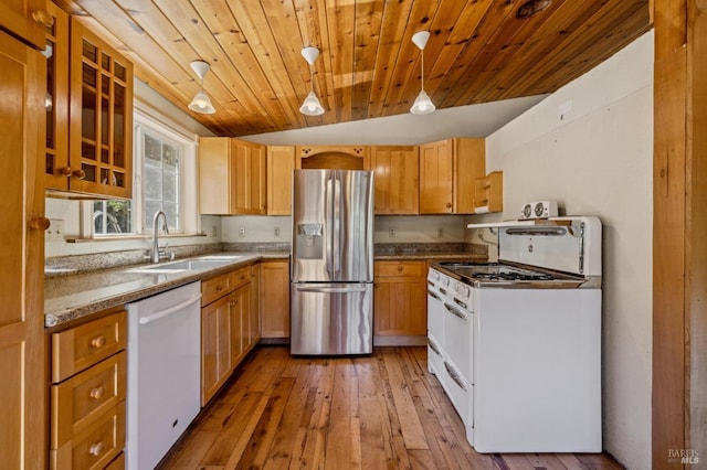 kitchen with light wood finished floors, hanging light fixtures, glass insert cabinets, a sink, and white appliances