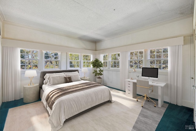 bedroom with ornamental molding, light colored carpet, and a textured ceiling