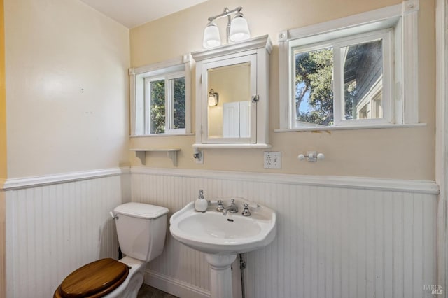 half bathroom featuring wainscoting and toilet