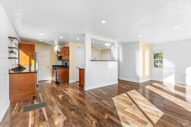 kitchen with a textured ceiling, dark hardwood / wood-style flooring, stainless steel appliances, and extractor fan