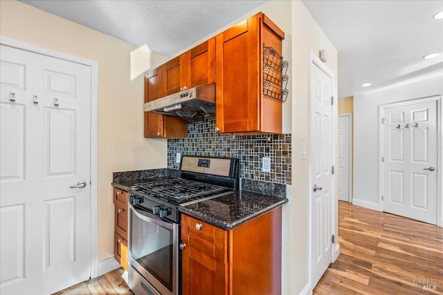 kitchen featuring decorative backsplash, light hardwood / wood-style flooring, dark stone counters, and stainless steel range with gas stovetop