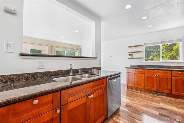 kitchen featuring dishwasher, sink, dark stone countertops, light wood-type flooring, and a textured ceiling