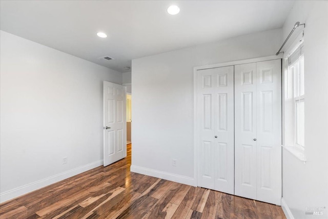 unfurnished bedroom featuring a closet and dark wood-type flooring