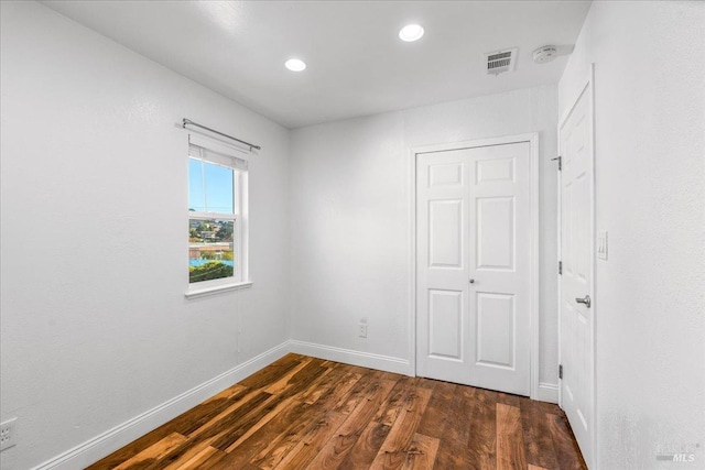 unfurnished bedroom with dark hardwood / wood-style flooring and a closet