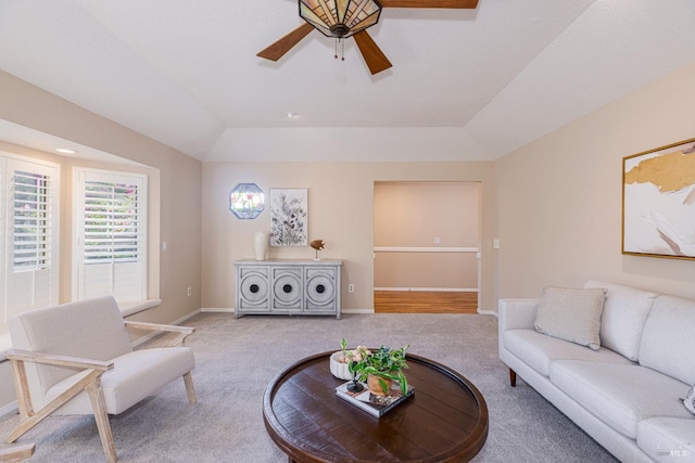 living room featuring a raised ceiling, vaulted ceiling, light carpet, and ceiling fan