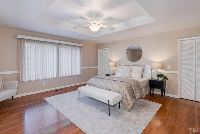 bedroom featuring dark hardwood / wood-style flooring, a tray ceiling, and ceiling fan