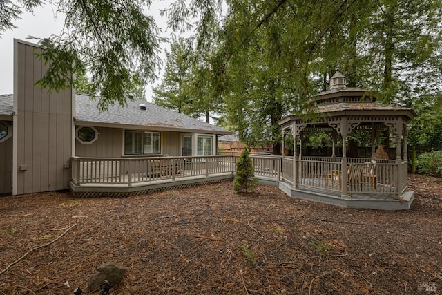 back of property featuring a gazebo and a deck