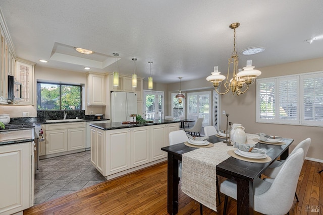 kitchen with sink, high end stainless steel range oven, white refrigerator, a kitchen island, and decorative light fixtures