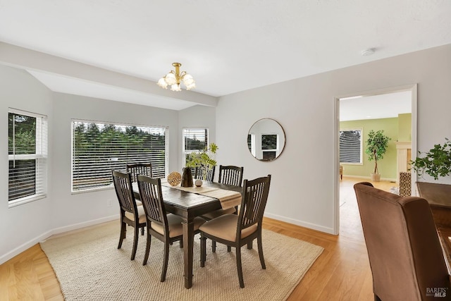 dining area with light wood-type flooring and a notable chandelier