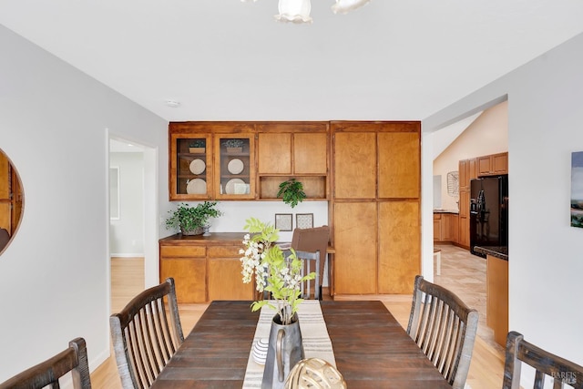 dining space with vaulted ceiling and light hardwood / wood-style floors