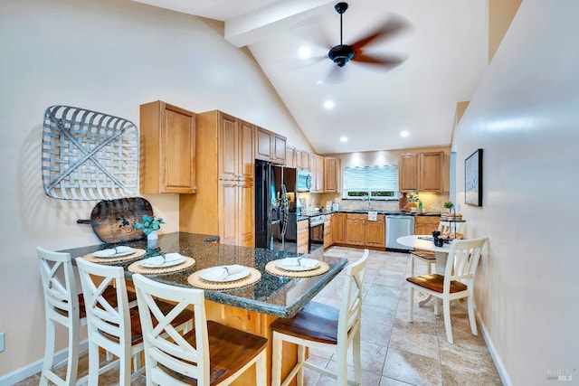 kitchen featuring a kitchen breakfast bar, stainless steel appliances, high vaulted ceiling, dark stone countertops, and ceiling fan