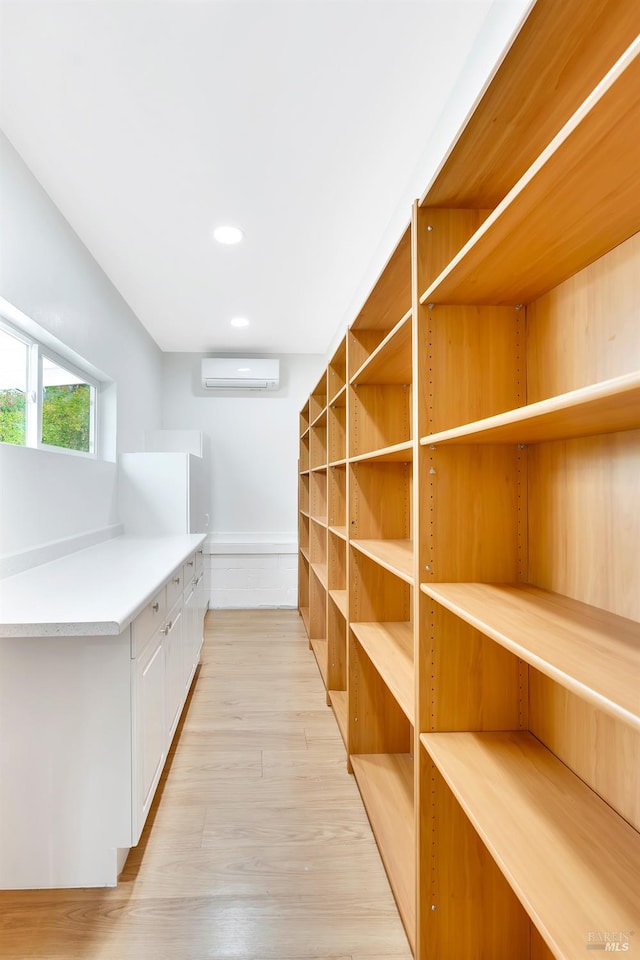 spacious closet featuring light hardwood / wood-style floors and a wall unit AC