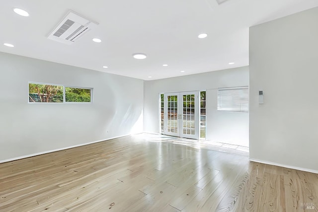 spare room featuring french doors, light hardwood / wood-style floors, and a wealth of natural light