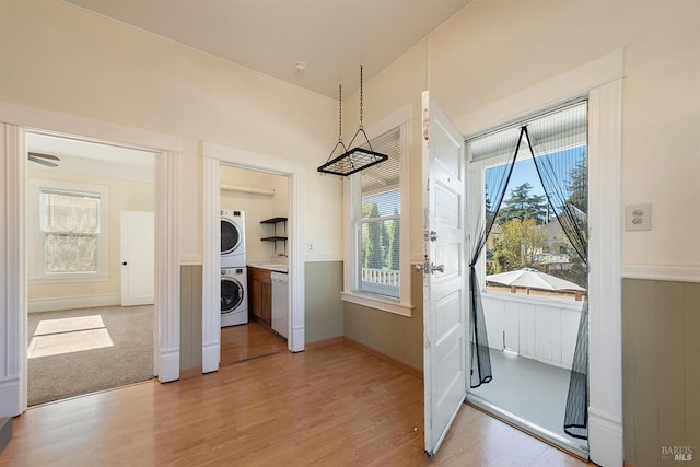 doorway to outside featuring light hardwood / wood-style floors and stacked washer and clothes dryer