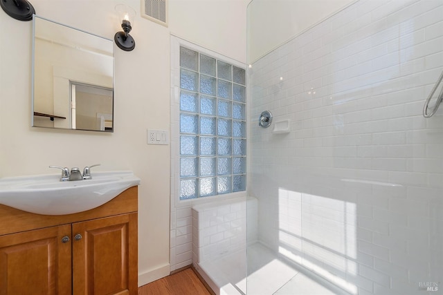 bathroom featuring tiled shower, vanity, and hardwood / wood-style floors