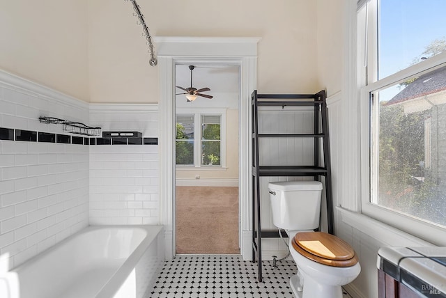 bathroom with a bath, toilet, and ceiling fan