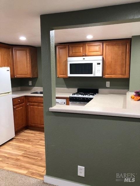 kitchen with white appliances and light wood-type flooring