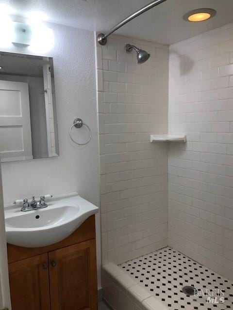 bathroom with tiled shower and vanity