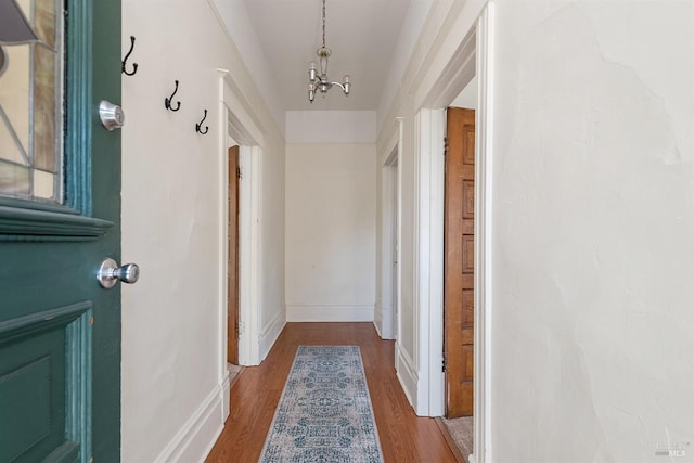 hall featuring an inviting chandelier and hardwood / wood-style flooring