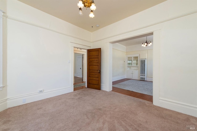 spare room with an inviting chandelier and carpet flooring