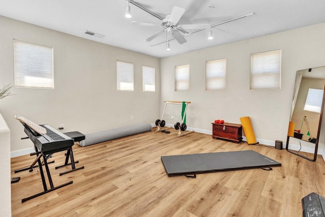 exercise room with track lighting, light hardwood / wood-style floors, and ceiling fan