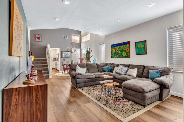 living room featuring lofted ceiling, hardwood / wood-style floors, and an inviting chandelier