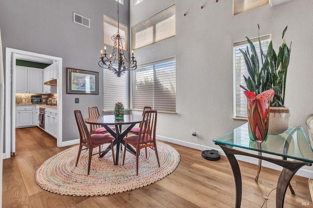 dining room with a high ceiling, a notable chandelier, and light hardwood / wood-style floors