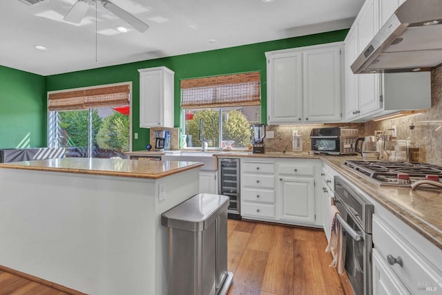 kitchen featuring appliances with stainless steel finishes, exhaust hood, white cabinets, and light hardwood / wood-style floors