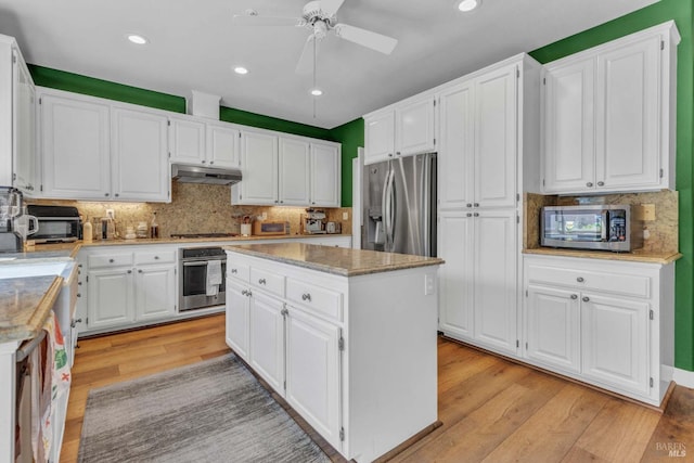 kitchen featuring white cabinetry, a kitchen island, stainless steel appliances, light hardwood / wood-style floors, and decorative backsplash