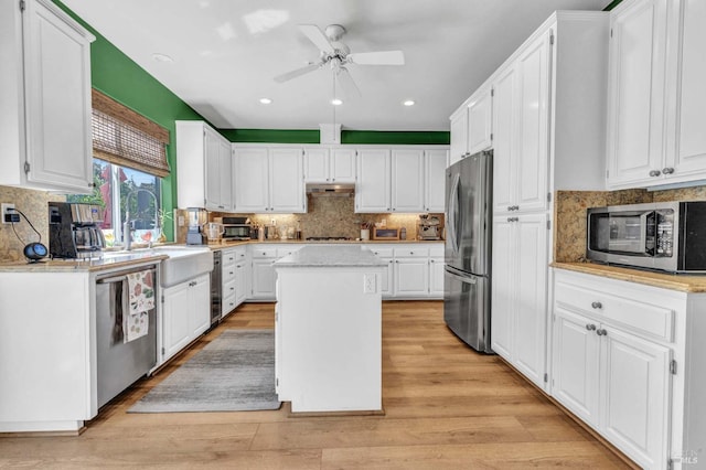 kitchen with sink, light hardwood / wood-style flooring, appliances with stainless steel finishes, a center island, and white cabinets