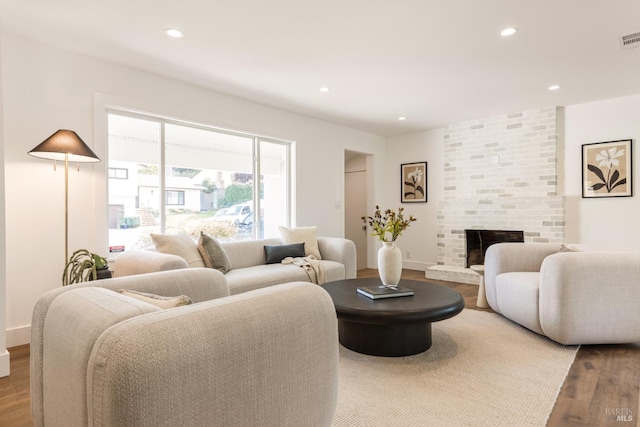 living room with hardwood / wood-style flooring and a brick fireplace