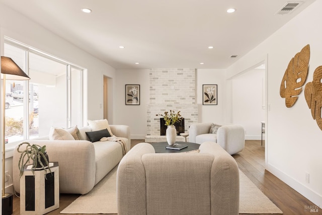 living room with light wood-type flooring and a brick fireplace