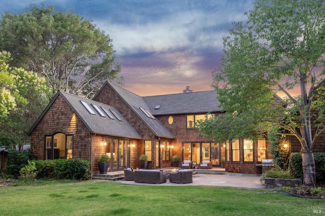 back house at dusk featuring a patio, an outdoor living space, and a yard