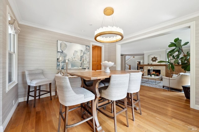 114 Van Tassel Ct, San Anselmo, CA 94960 - dining area featuring crown molding, a lit fireplace, baseboards, light wood finished floors, and a notable chandelier