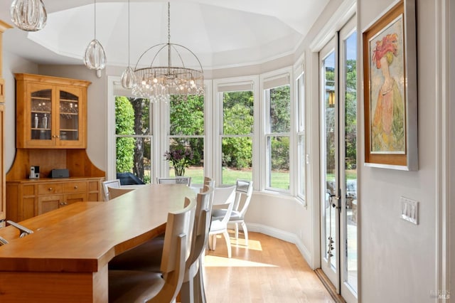 dining room with a notable chandelier, light wood-type flooring, vaulted ceiling, and a healthy amount of sunlight