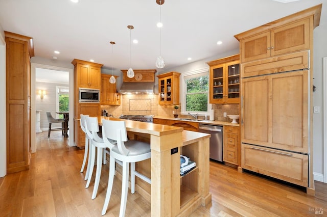 kitchen with decorative backsplash, light countertops, glass insert cabinets, light wood-style floors, and built in appliances
