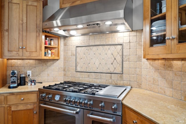 kitchen featuring wall chimney exhaust hood, decorative backsplash, and stainless steel range