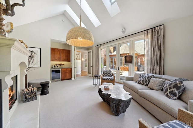 carpeted living room with high vaulted ceiling, beverage cooler, a skylight, and french doors