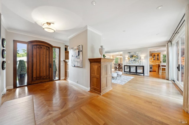 entryway with ornamental molding and light parquet floors